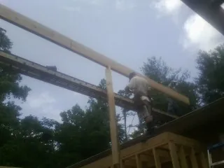 Carpenter setting a ridge beam over a new addition frame — Ice Dam Removal by Roofing Brothers in Buchanan