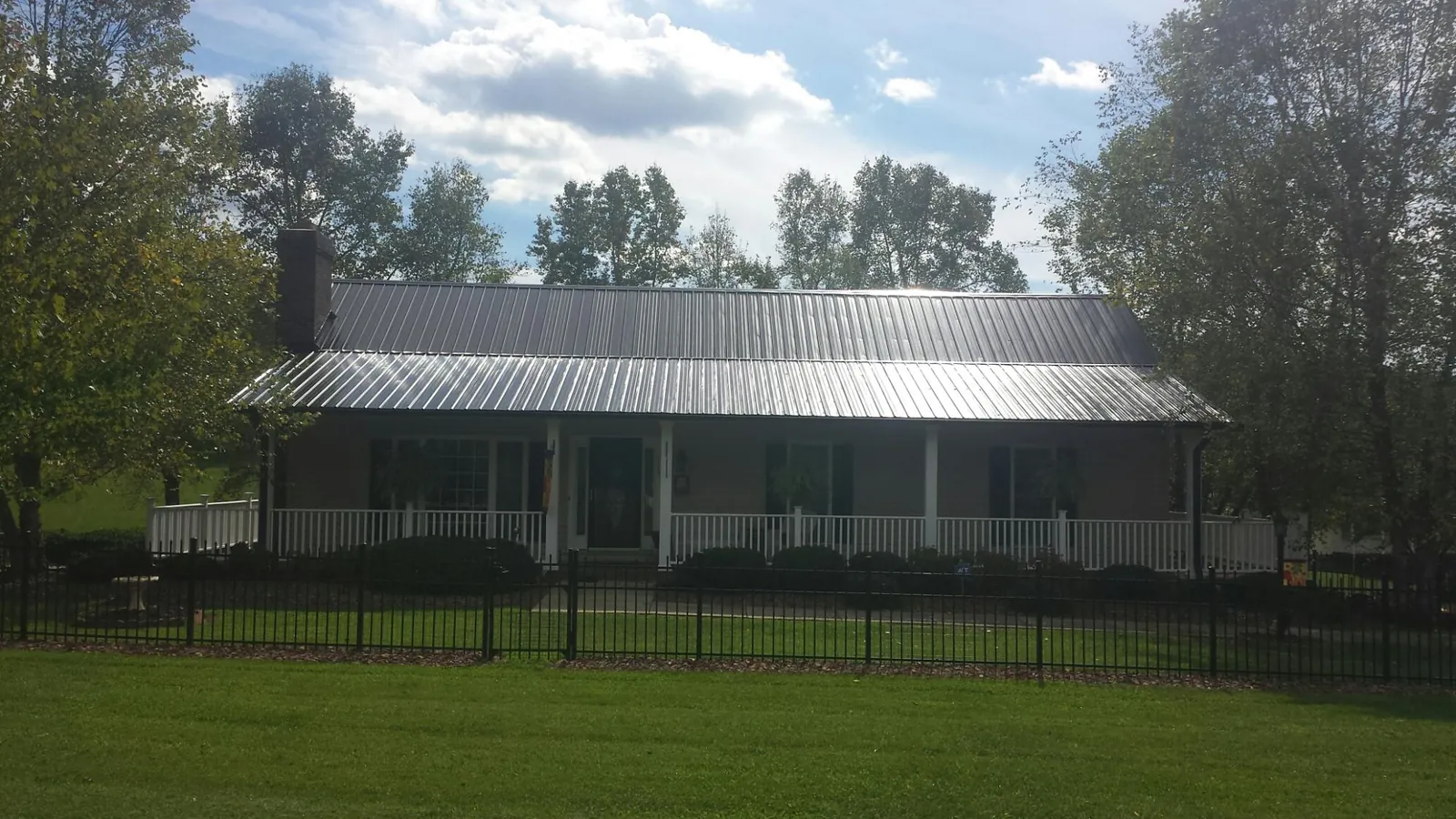 Gray metal roof on a brick ranch with a full width front porch — Gutter Guard Installation work by our crew in Buchanan
